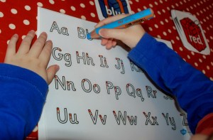 Using his letter tracing sheet to spell out words