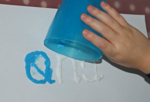 sand words - using a cup to sprinkle the sand onto the glue