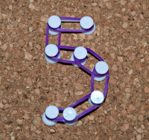 Creating numbers on our cork coasters with drawing pins and loom bands