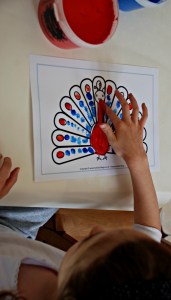 Finger painting on a peacock colouring page from Activity village