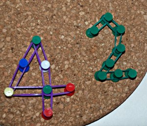 Practicing number formation on the cork hot pot stands with our drawing pins and loom bands on ofamilyblog
