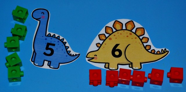 Matching the correct number of snap cubes to the correct number on the Free to download Numbered Dinosaurs from Twinkl