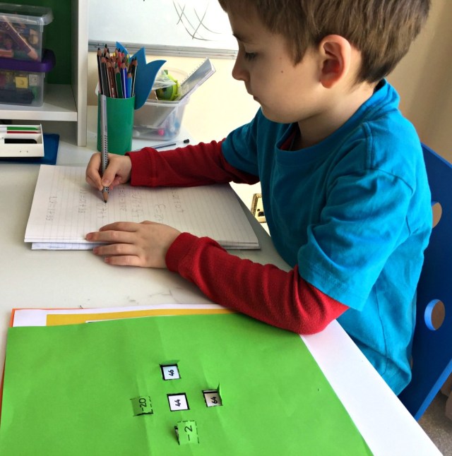 Working out his own sums using a 100 square and a home-made number flap