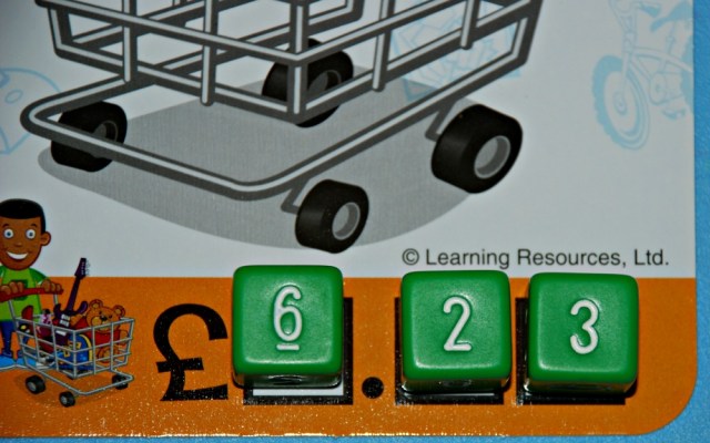 Buy It Right game from Learning resources. The bottom of the shopping cart has three spaces for the dice to go which represent the amount an item costs