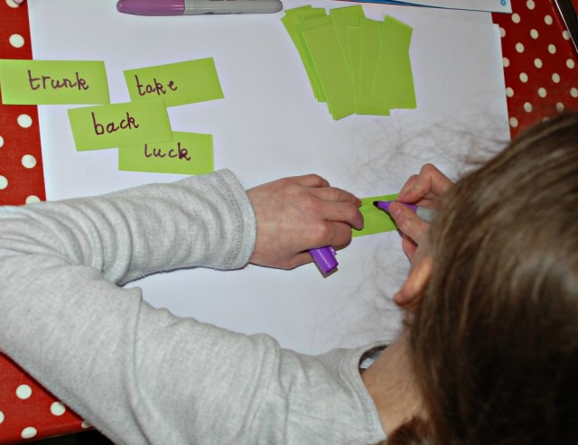 Writing words on small pieces of paper to stick inside the spelling folder