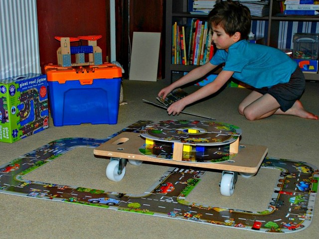 Using his giant road floor puzzles to build creative roads