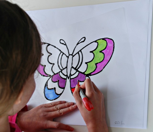 Colouring in our home-made butterfly suncatchers with sharpies